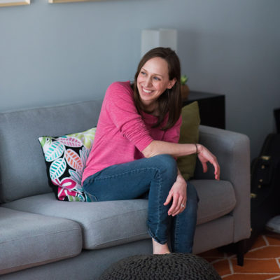 Wedding photographer, Allie Siarto, sits on a couch in front of a large print
